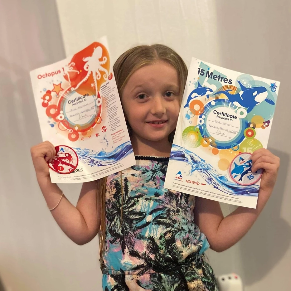 Girl holding Swim Steps Swim School Certificates and Swimming Badges
