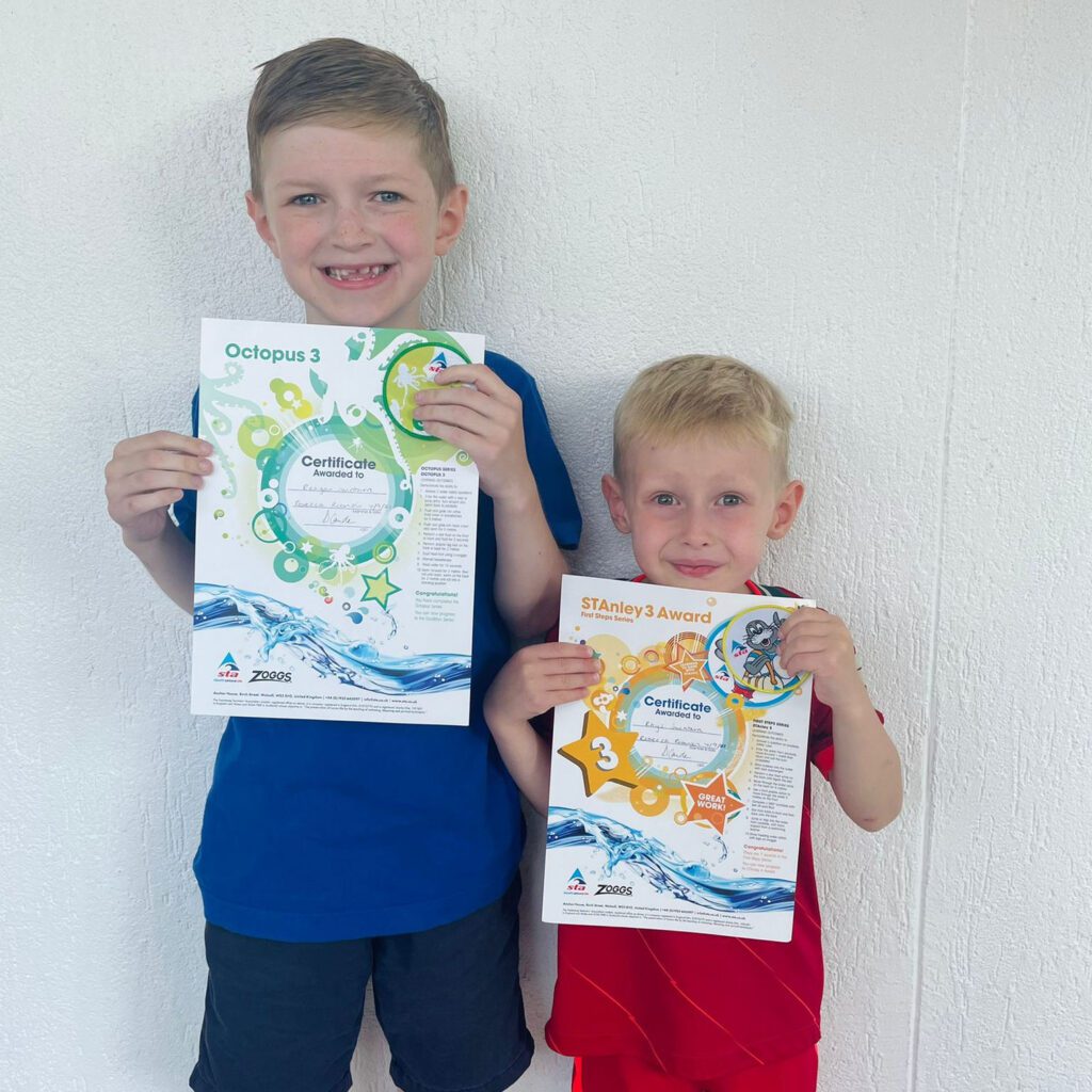 Two young boys holding their Swim Steps Swim School Learn to Swim Certificates
