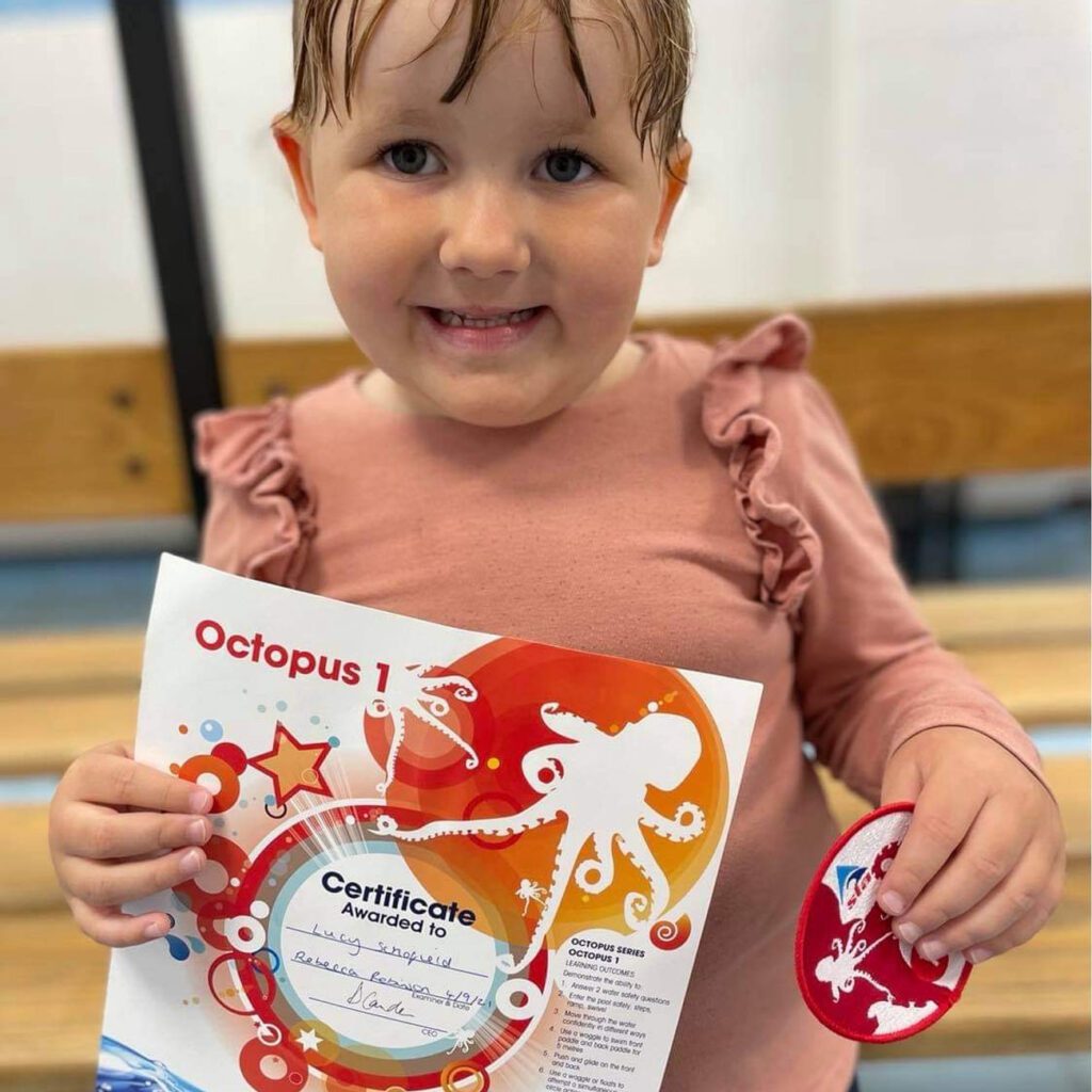Girl showing off swimming certificate awarded by Swim Steps Swim School