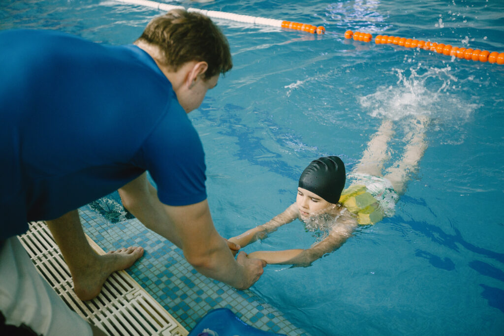 Girl learning to swim with with a swimming teacher